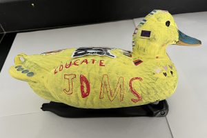 Duck decoy painted yellow with stickers on it