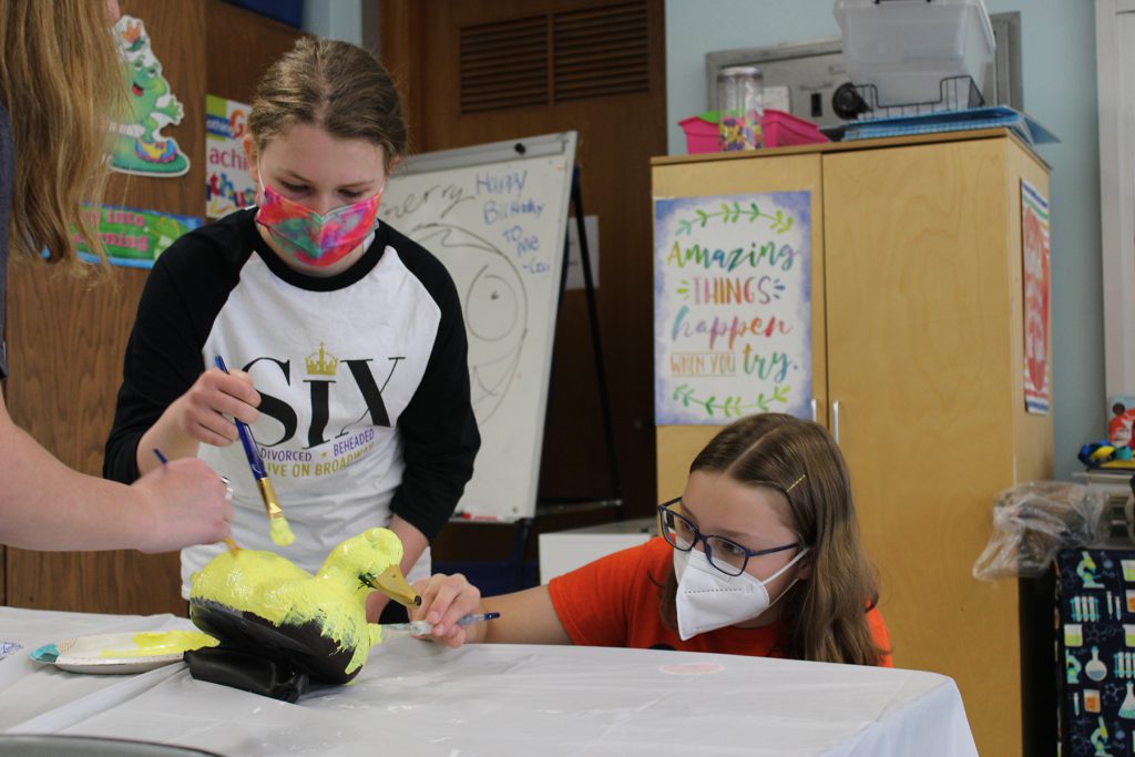 Two students painting duck decoy.