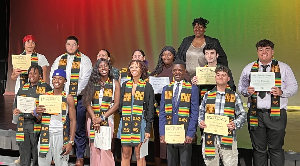 Group of students standing on a stage wearing Kente stoles.