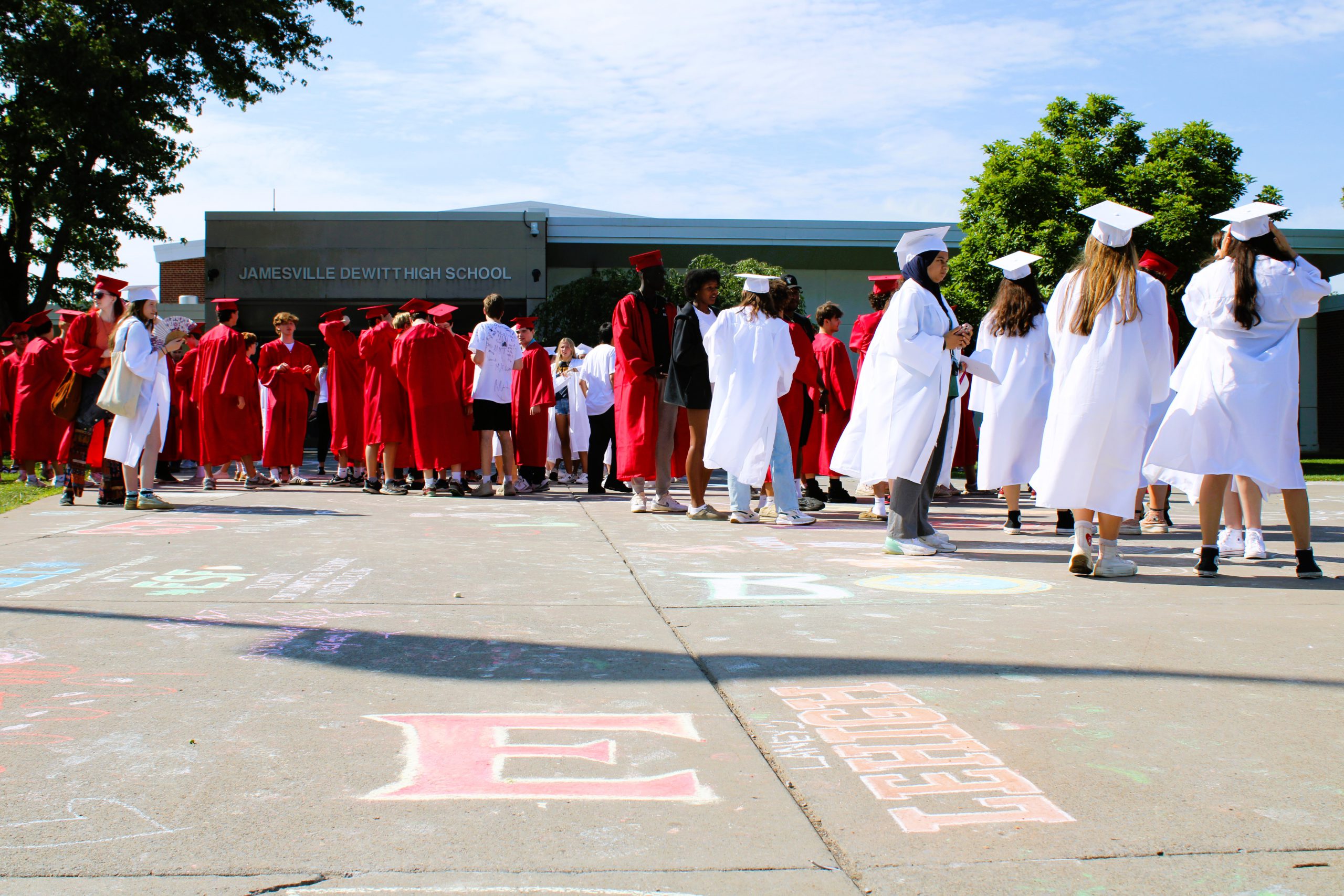 Image of 2024 seniors in caps and gowns gathered outside the high school.