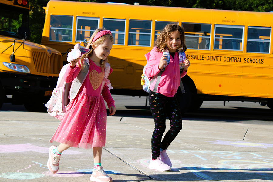 two students walking into Jamesville Elementary School wearing pink and smiling.