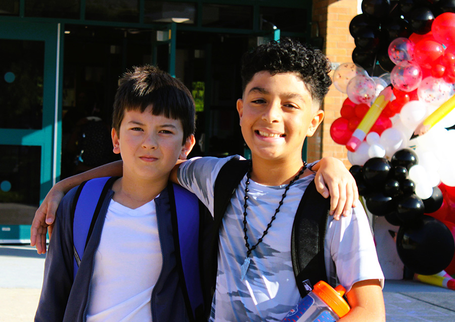 two students hug and pose for a photo on the first day of school.