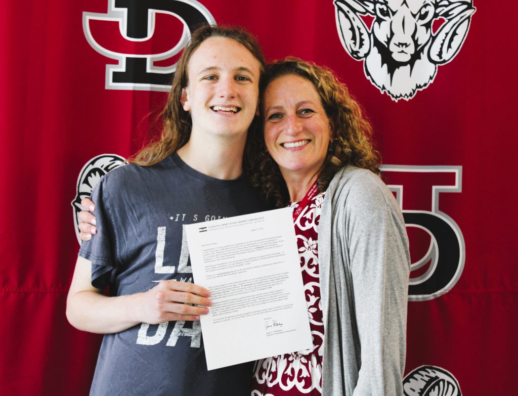 J-DHS math teacher Anna Cabral Drew poses with her son Peter Drew after presenting him with a 2024 National Merit Scholarship Semifinalist award letter.