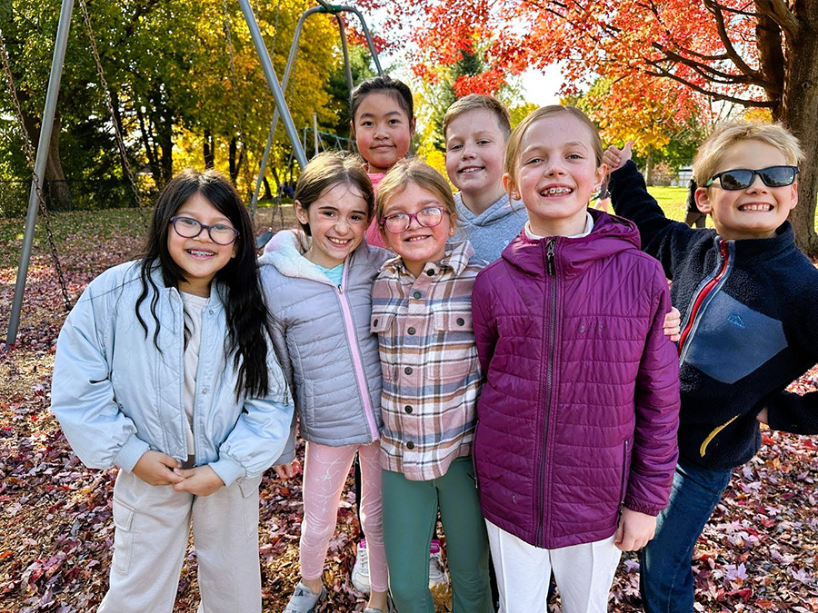 students pose for photo while on the playground during fall.