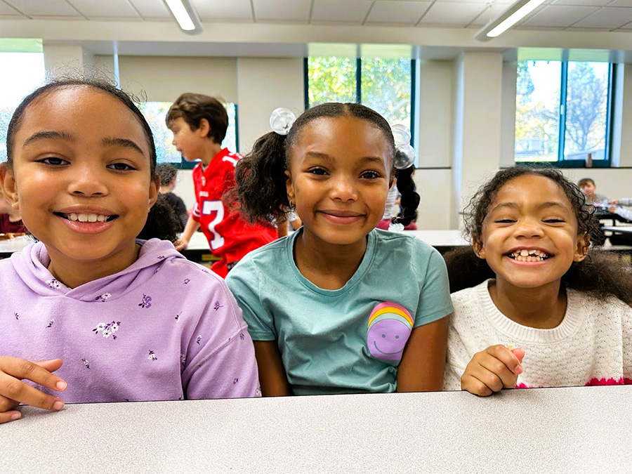 three students smile and pose for group photo.