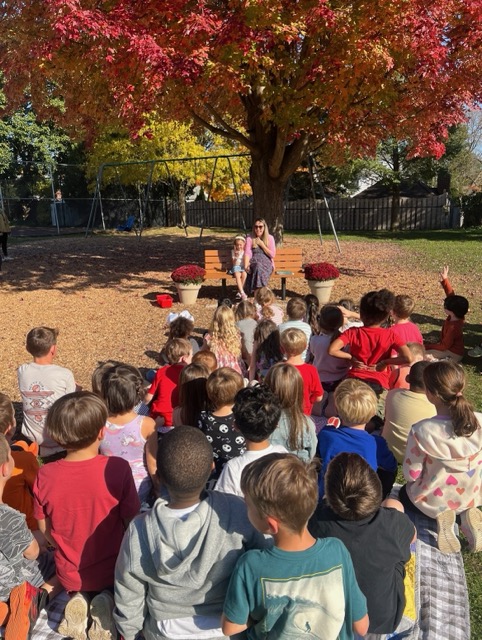 Julia Blanchard Aloi and daughter Grace read a story to students in memorial bench dedication.