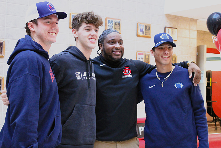 Student-athletes pose with a coach after National Letter of Intent Signing event. 