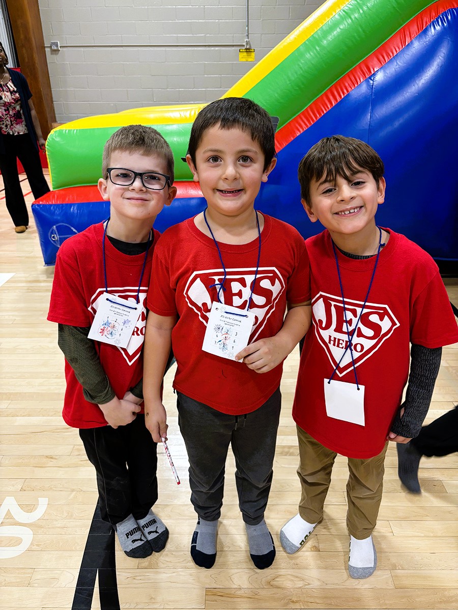 Three students wearing JES Hero shirts pose for photo during winter carnival.