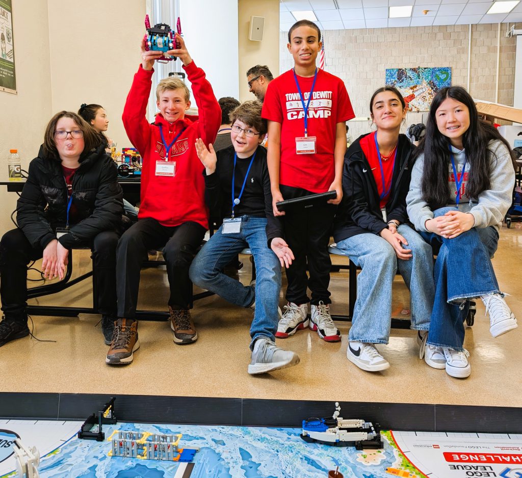 J-DMS ROM team poses for photo with lego robot.