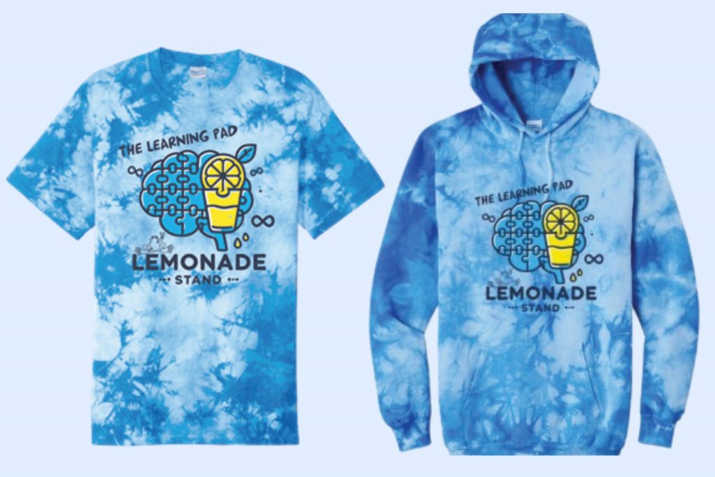 A blue tie dye t-shirt and sweatshirt with art of a brain made of puzzle pieces and a glass of lemonade. 