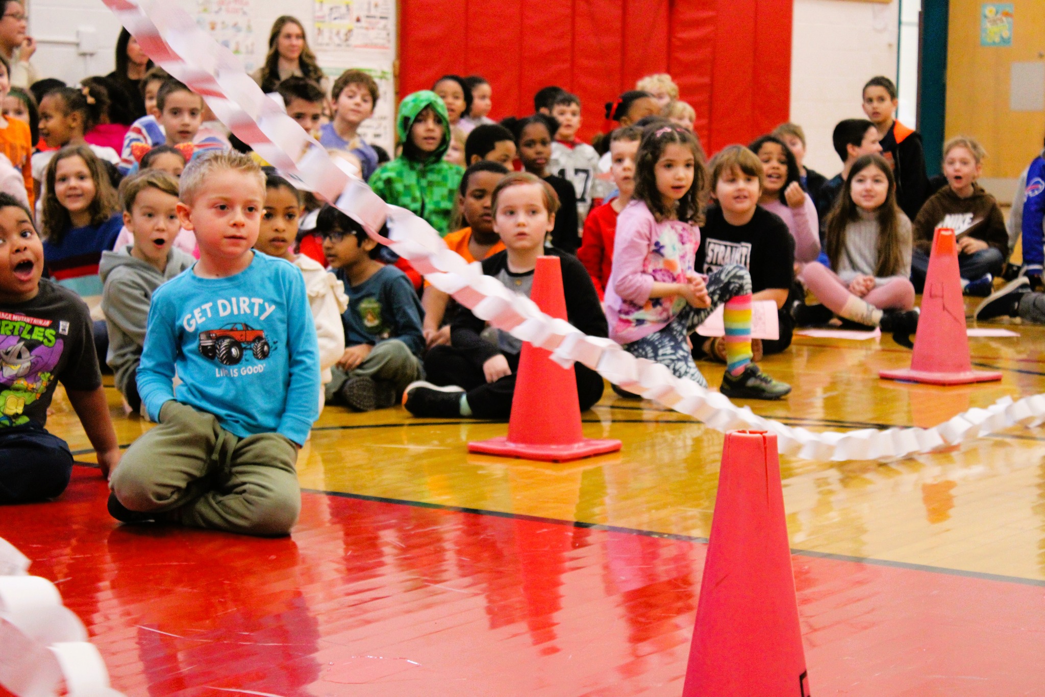 Students look at paper chain length during kindness assembly.